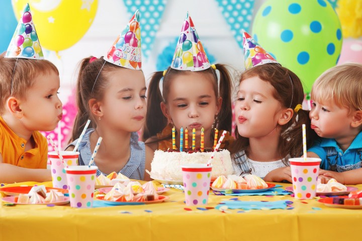 a little girl sitting at a table with a birthday cake