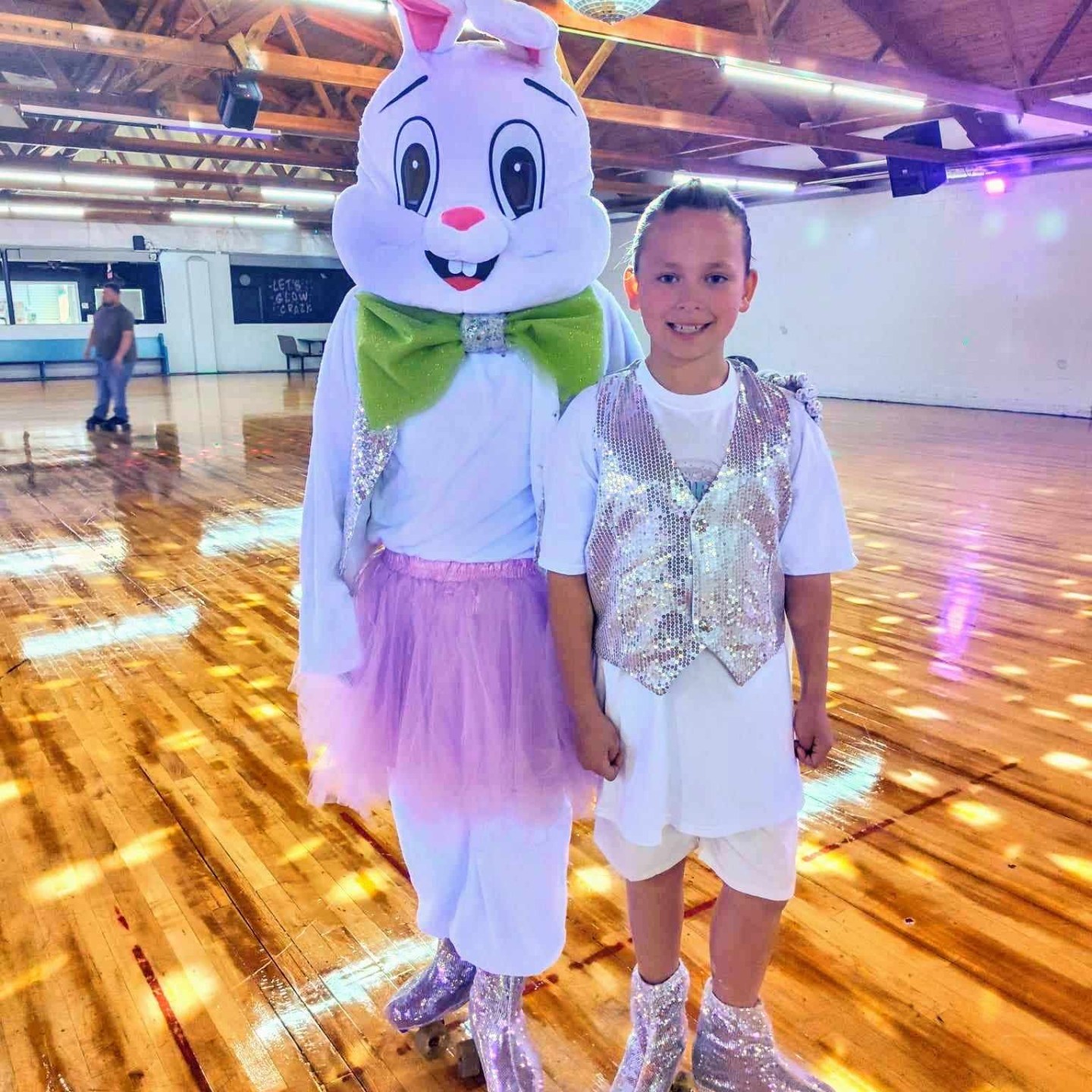 Child and person in bunny costume roller skating in a rink.