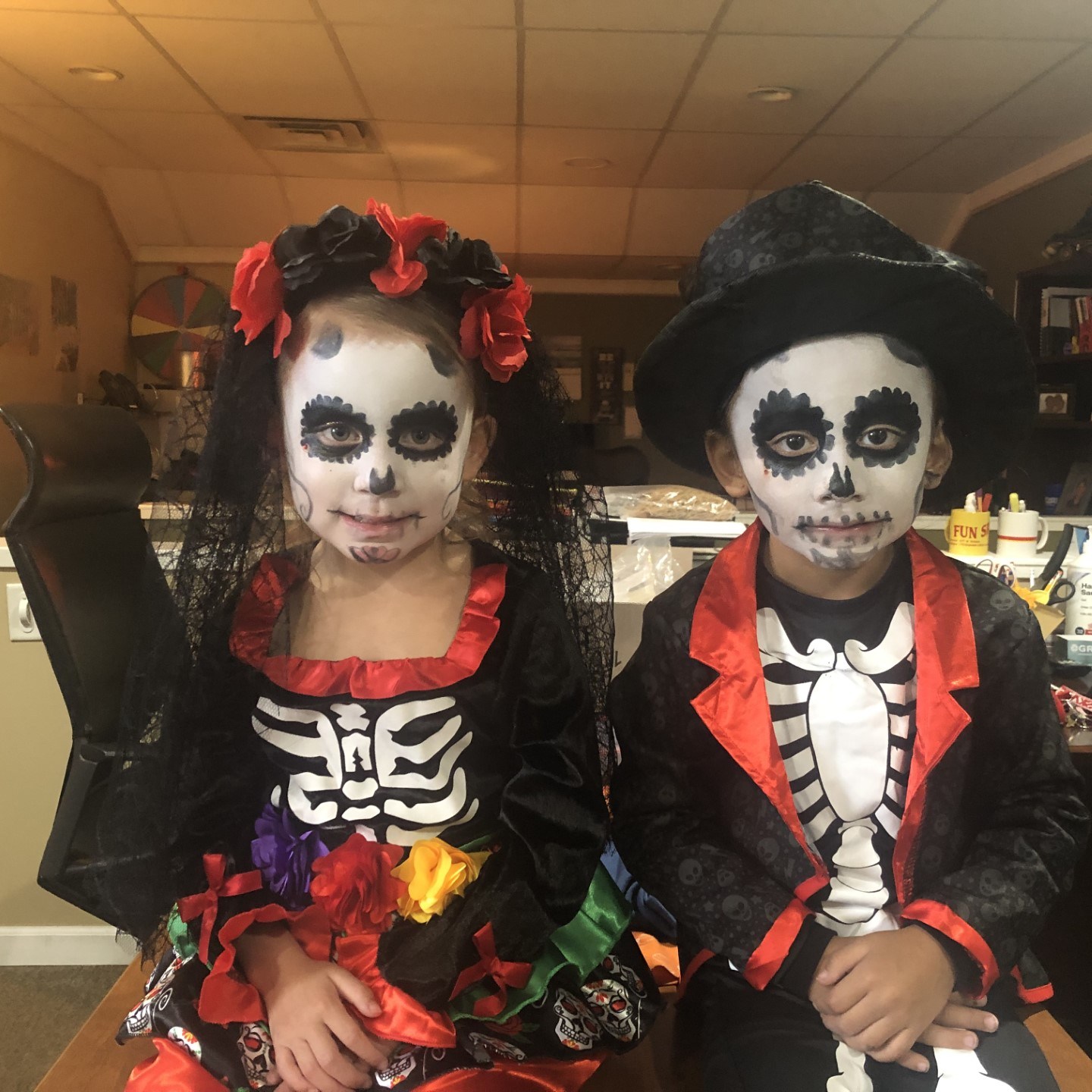 Two children in skeleton costumes and face paint, celebrating Day of the Dead.