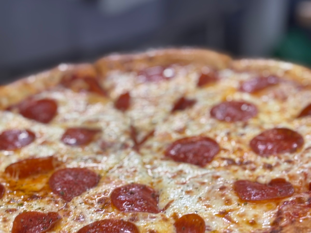 Pepperoni pizza with melted cheese on a metal tray.
