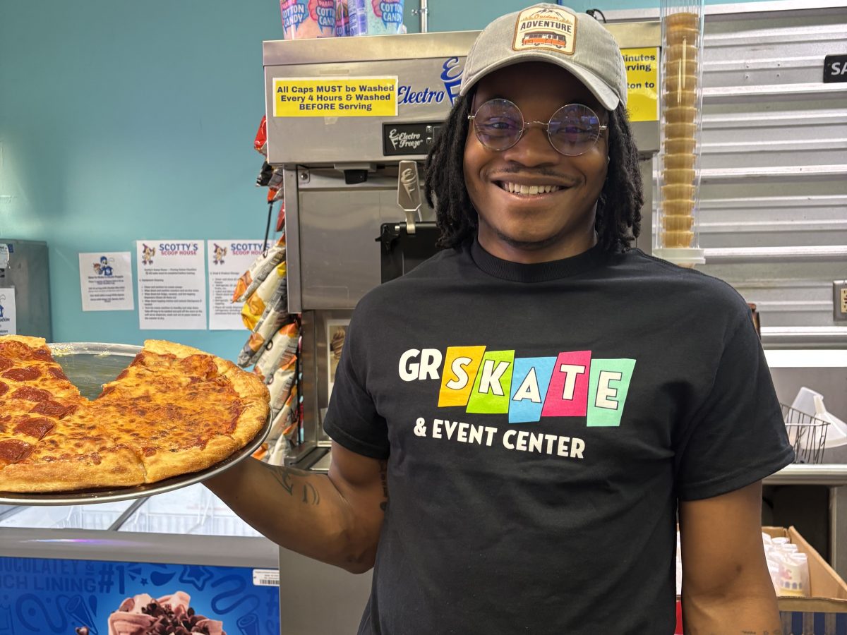 Person holding a large slice of pizza in an ice cream shop.