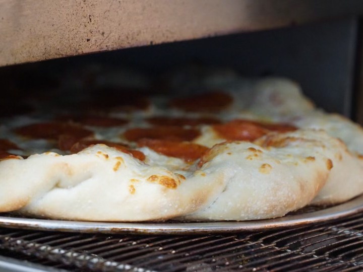 Pizza with pepperoni baking on oven rack.